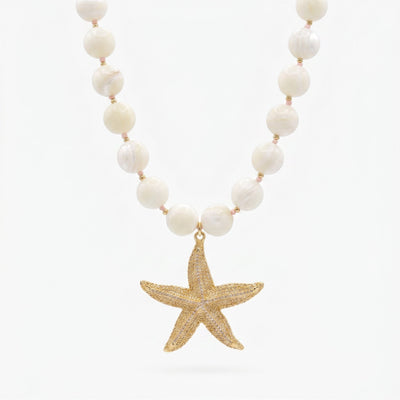 Pearl beaded necklace with large gold starfish pendant on white background