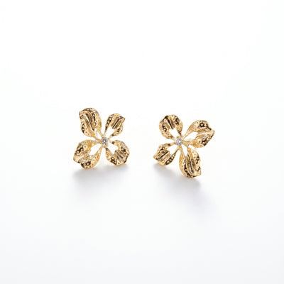 Sun Petal gold flower stud earrings with clear center stone photographed in natural light