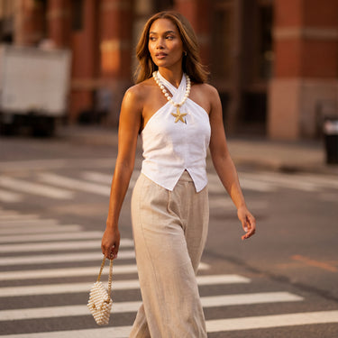 Pearl beaded necklace with gold starfish pendant worn by a model outdoors on a city street