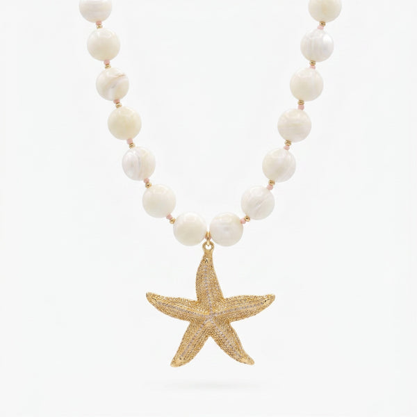 Pearl beaded necklace with large gold starfish pendant on white background