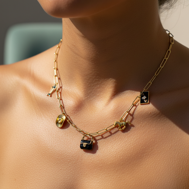 Model wearing black enamel bag charm on layered gold charm necklace