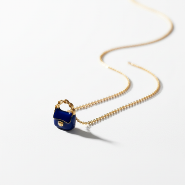 Flat lay of midnight blue enamel gold-plated handbag charm in natural light