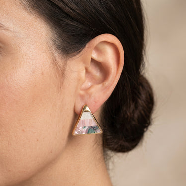 Triangle stud earring in gold brass with pink mother of pearl inlay, worn on a model