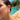 Shell drop earrings with gold trim and blue teardrop charm worn by a model outdoors near a pool