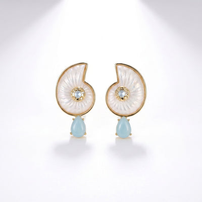 Pair of nautilus shell shaped earrings in white mother of pearl with gold trim and light blue teardrop stone drops