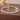 Close-up of gold stretch tennis bracelet on brown jewelry block.
