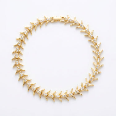 Gold plated brass fishbone bangle bracelet with organic reef-inspired pattern, flat lay on white