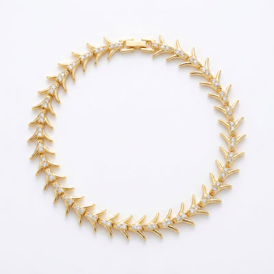 Gold plated brass fishbone bangle bracelet with organic reef-inspired pattern, flat lay on white