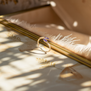 Gold purple horizon ring with a purple gemstone on a textured surface with natural light
