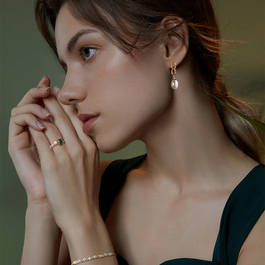 Elegant woman wearing gold pearl drop earrings.