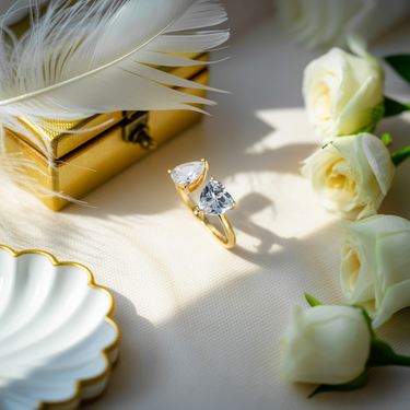 Key West Love Ring with a large diamond on a table with white roses and a feather