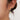 Woman wearing coastal gold shell drop earrings with pearl.