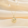 Gold nautilus pendant necklace with pearls on soft fabric.