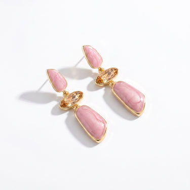 Drop earrings with pink marbled resin panels, champagne crystal accents, and gold tone setting on white background