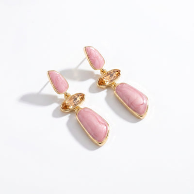 Drop earrings with pink marbled resin panels, champagne crystal accents, and gold tone setting on white background
