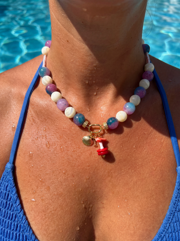 Purple agate and mother of pearl beaded necklace with coastal coral charms on neutral background