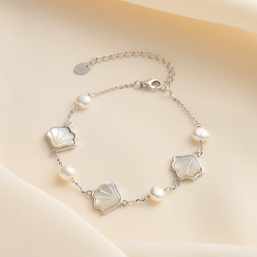 Rhodium plated seashell charm bracelet with freshwater pearls.