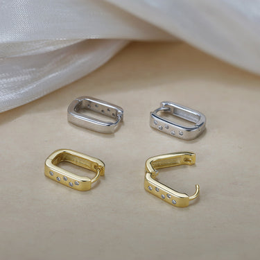 Gold and silver ShineLine Huggie earrings displayed on neutral background.