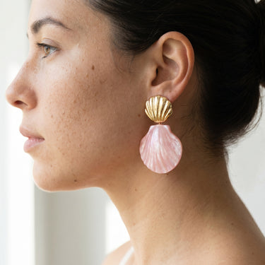 Drop earring with gold brass shell stud and pink pearlescent shell pendant, worn on a model