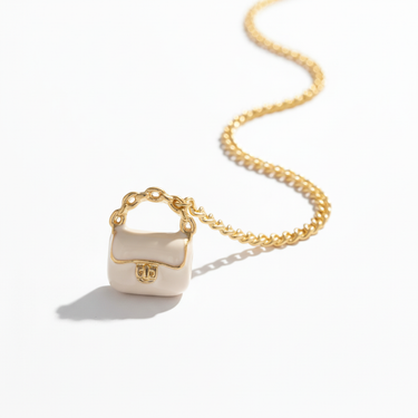 White enamel bag charm flat lay in natural light on neutral surface