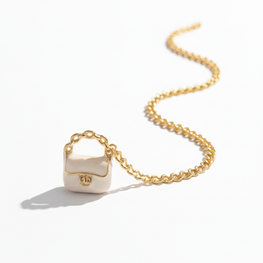 Close-up of white enamel miniature handbag charm with gold loop detail