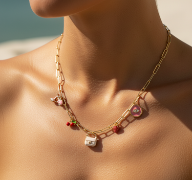 Model wearing white enamel bag charm on a layered gold necklace